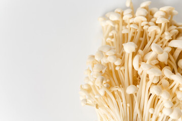 Heap of little white enoki mushrooms on neutral white background, close-up