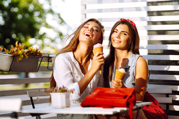 Two young female friends having fun and eating ice cream. Young women enjoy summer and vacation. 