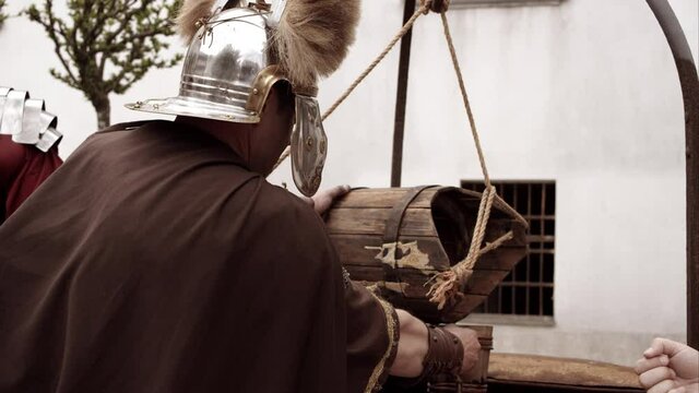 Centurion Pours Water From A Well Into A Wooden Cup And Hands It To Somebody