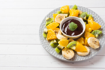 Chocolate fondue with fruit on white table. concept summer party. Copy space
