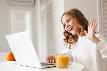 Photo of cheerful girl taking video call on laptop and waving hand