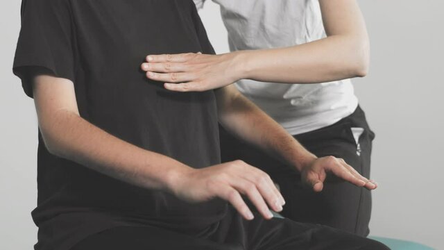 Closeup of physiotherapist exercising with disabled person on a therapy table.