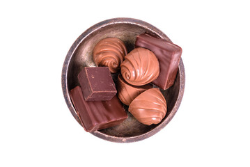 Chocolate candies in a metal vase, top view, isolated on white background
