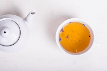 Teapot and cup of green tea with flower petals on the table, top view