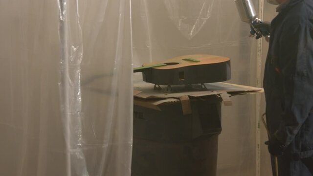 Air spraying a first coat of blue paint on an old guitar in a restoration project.