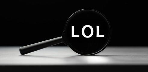Magnifying glass with text LOL on wooden table. Concept of search
