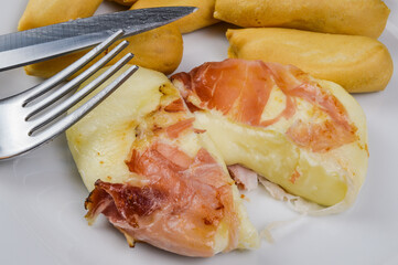 Ready Tomino (delicious cow's milk cheese from Piedmont, Italy) rolled with speck (italian smoked ham), with a fork served with grissini.
