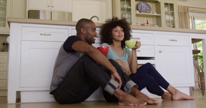 Happy mixed race couple drinking coffee in their kitchen