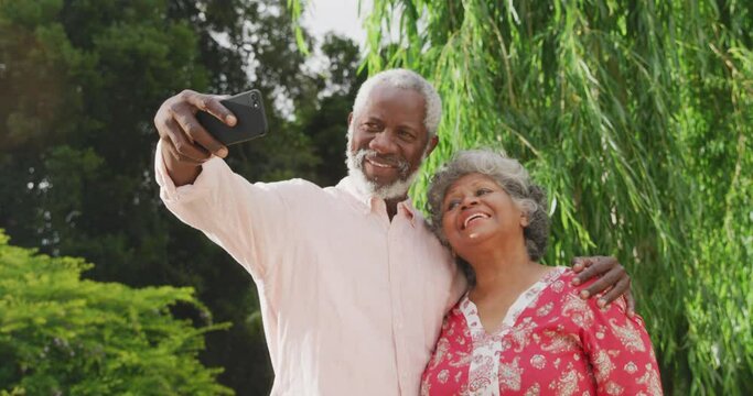 A senior African American couple in the garden taking a picture in social distancing