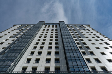 The facade of a high-rise building on a background of blue sky with clouds.