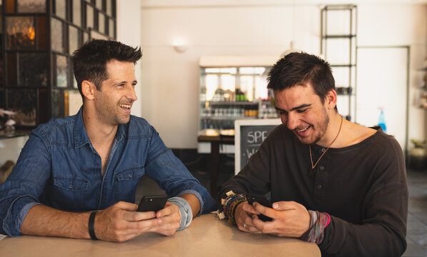 Caucasian men in a coffee shop using their phone 