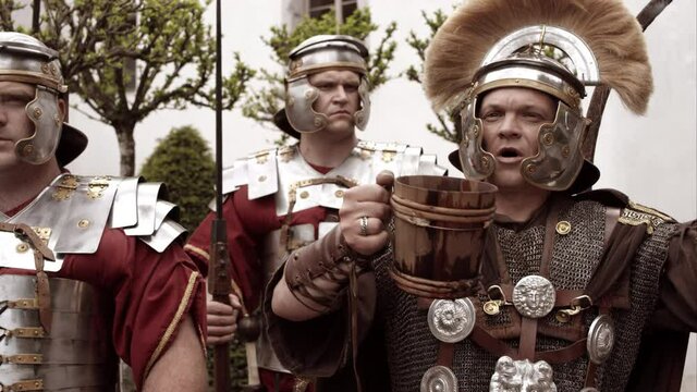 Centurion And Two Soldiers Shout Triumphantly While Centurion Holds Drink