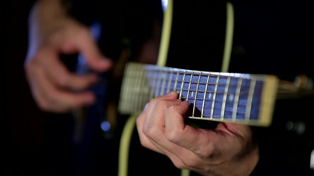 Male hands playing the guitar with a refocus from one hand to another