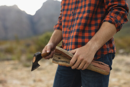 Mid section view of man holding wood and a ax 