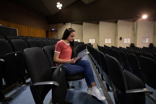 Side view of student reading a text in a theater