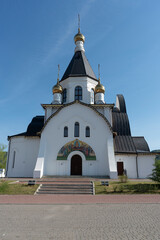 White Church on a background of blue sky. Church with a bronze roof and golden domes.