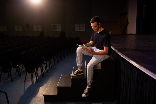 Side view of student reading a text in a theater