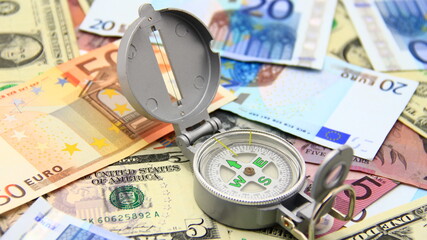 Small compass on international paper money. Where to move? Direction in economy to be found.