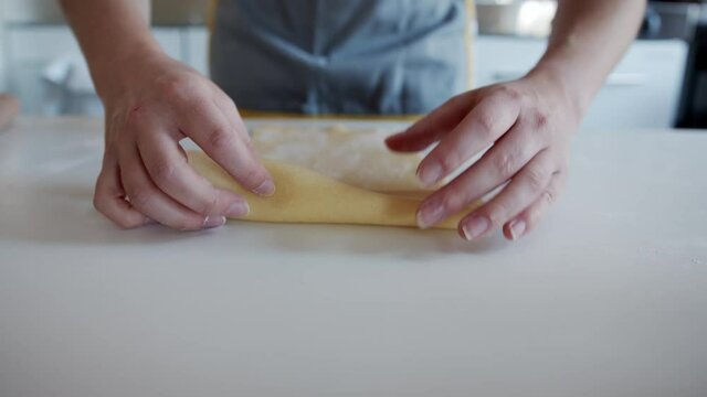 Hands Rolling Up Pasta Dough, Ready to cut into tagliatelle Pasta. Close up, Following.