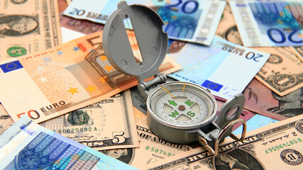 Small compass on international paper money. Where to move? Direction in economy to be found.