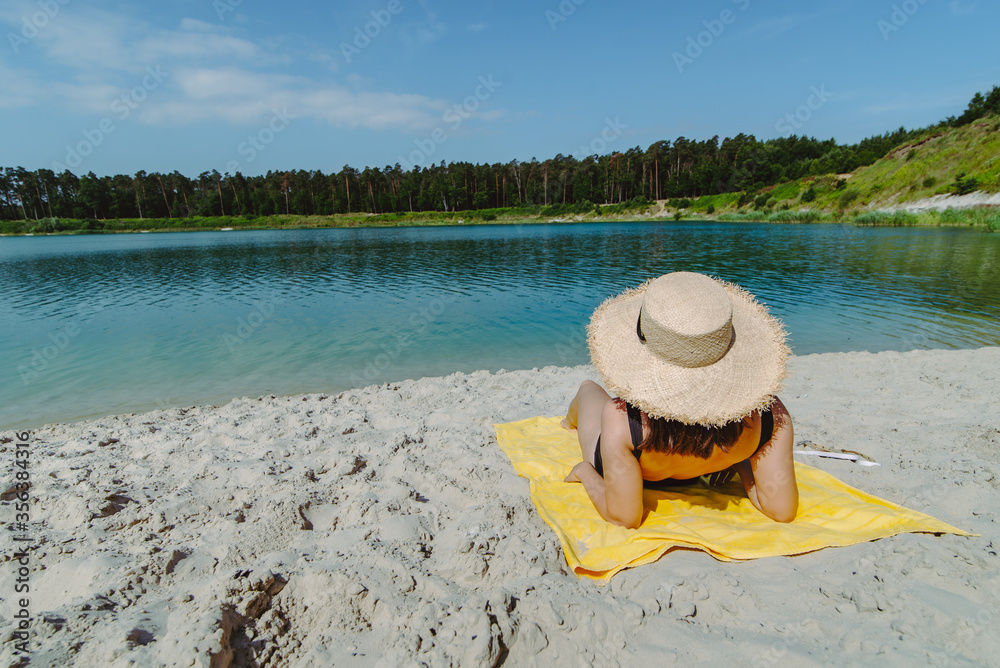 Wall mural woman laying on yellow blanket sunbathing at sand beach