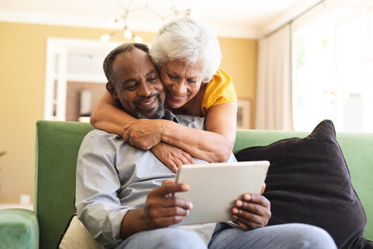 Senior African American couple cuddling and using laptop in a canape