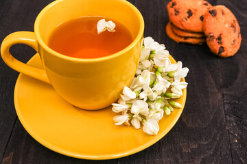 yellow cup of herbal tea and acacia closeup. herbal tea from acacia as a concept of healthy nutrition. background with a cup of tea, cookies and acacia flowers.