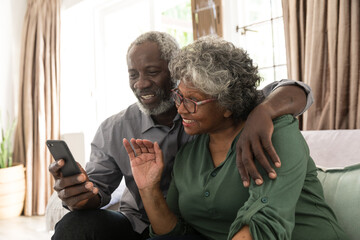 An African American couple smiling and looking at a smartphone