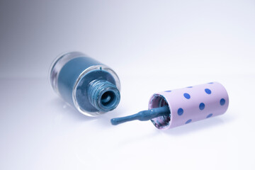 A bottle with spilled blue nail polish on white background. nail lacquer. Nail manicure concept. Isolated, copy space. 