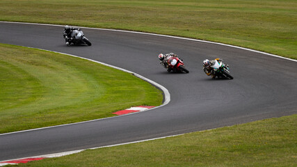 A panning shot of multiple racing bikes cornering on a track