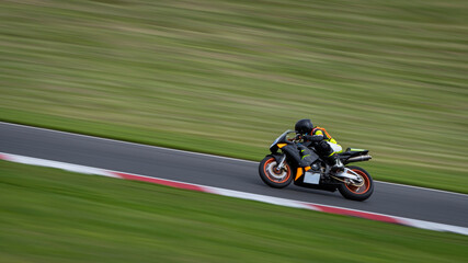 A panning shot of a black racing bike cornering on a track