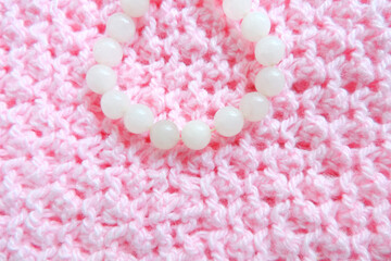  bracelet in white pearl beads on a  textured knitted surface    