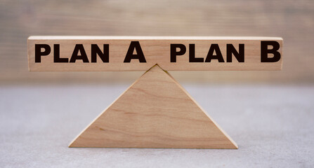 The concept of the balance of words between PLAN A and PLAN B on wooden scales on a light background