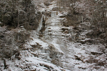 Ice, icicles over the rocks in a cold winter forest.