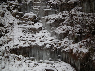 Naklejka na ściany i meble Ice, icicles over the rocks in a cold winter forest.