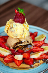 waffles with strawberry, ice cream and banana served on plate, ready to eat