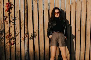 young brunette girl in a leather jacket and shorts in sunglasses on style