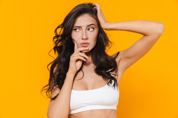 Image of young perplexed woman in swimsuit thinking and looking aside