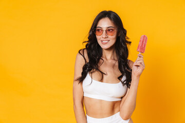 Image of happy nice woman in swimsuit smiling and holding ice cream