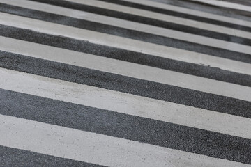 High angle detail view of pedestrian zebra crossing on wet street tarmac on rainy day
