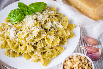 Delicious farfalle pasta with pesto sauce on wooden rustic background