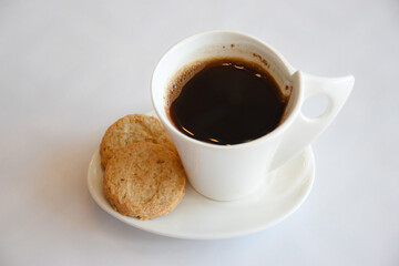 Side view of hot black coffee in white cup with two oat biscuits on white background, Have a nice day concept