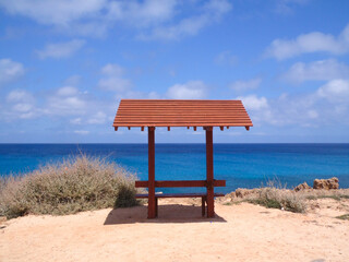 Fototapeta na wymiar Beutiful lonely wooden sitting bench in front of the sea, blue sky with clouds