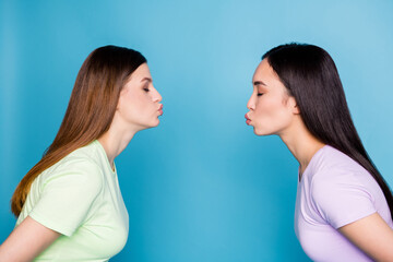 Profile photo of two affectionate lesbians couple young students fellowship send air kisses stand opposite eyes closed blind date wear casual t-shirts isolated blue color background