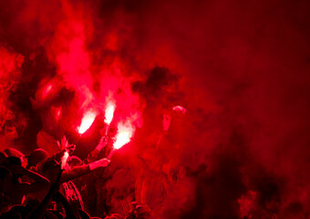 Football fans lit up the lights, flares and smoke bombs. Protest concept. Red smoke and torches