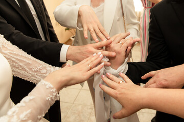 Bride, groom and group of wedding guests shows wedding rings