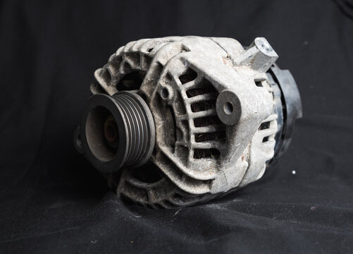 Used, dirty unclean alternator car part shot on a black background to highlight the silver metal piece of a car taken to be replaced with a brand new part. Pulley an electric parts discarded rubbish
