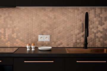 Black kitchen with hexagonal, copper wall tiles