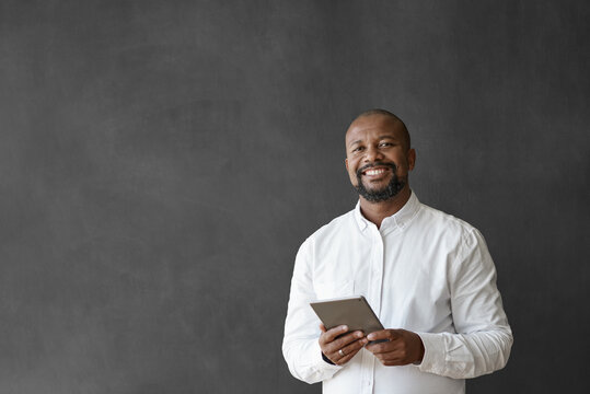 Smiling African American businessman using a tablet by a chalkboard