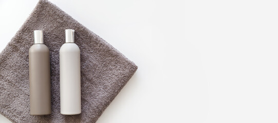 Plastic bottles of shampoo and body gel on towel isolated on white. Flat lay